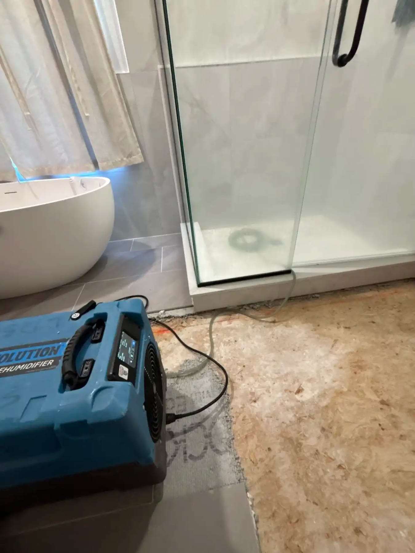 Bathroom with the tile removed to the subfloor and a dehumidifier running