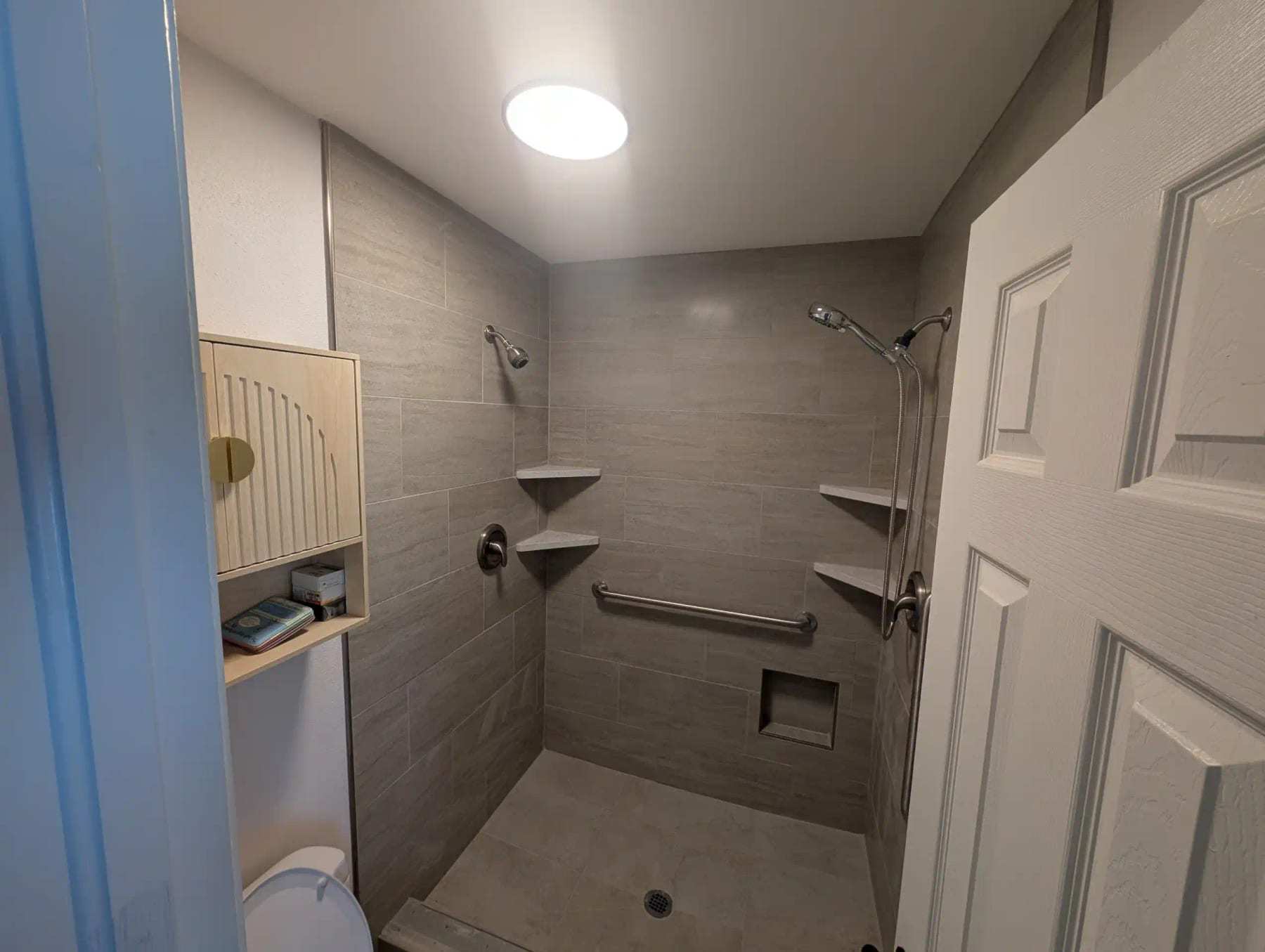 Finished tiled shower with built-in niches and a grab bar